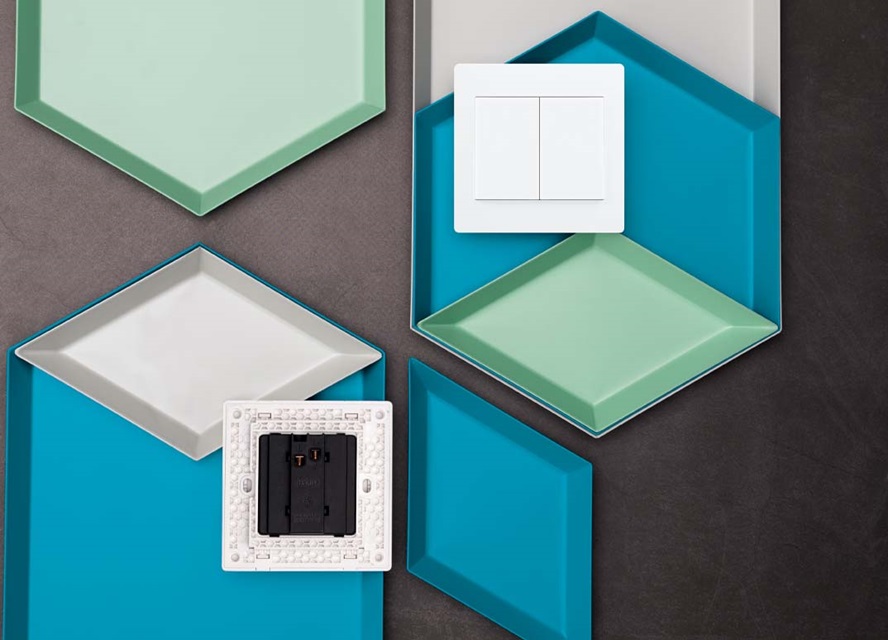 Electrical socket and switch on colorful geometric background, showcasing modern wiring accessories