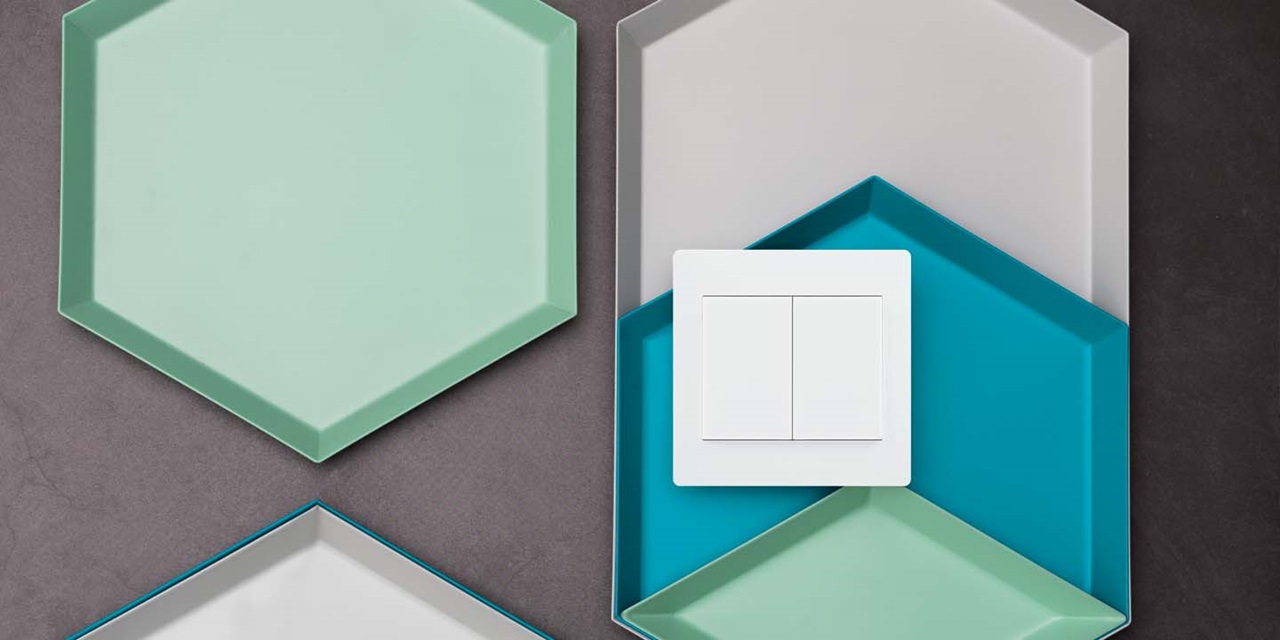 Modern light switch on a geometric pattern background with hexagonal plates in various shades of green and blue