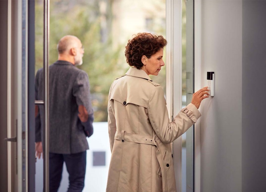 Person using a modern access control system on a wall next to glass doors