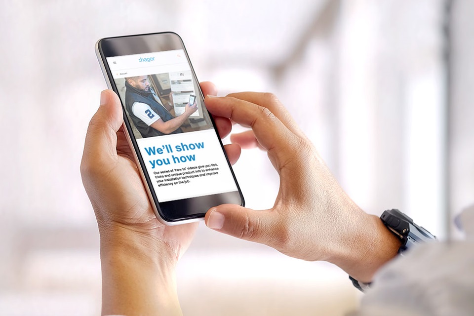 Person holding a smartphone with Hager website showing an educational service advertisement