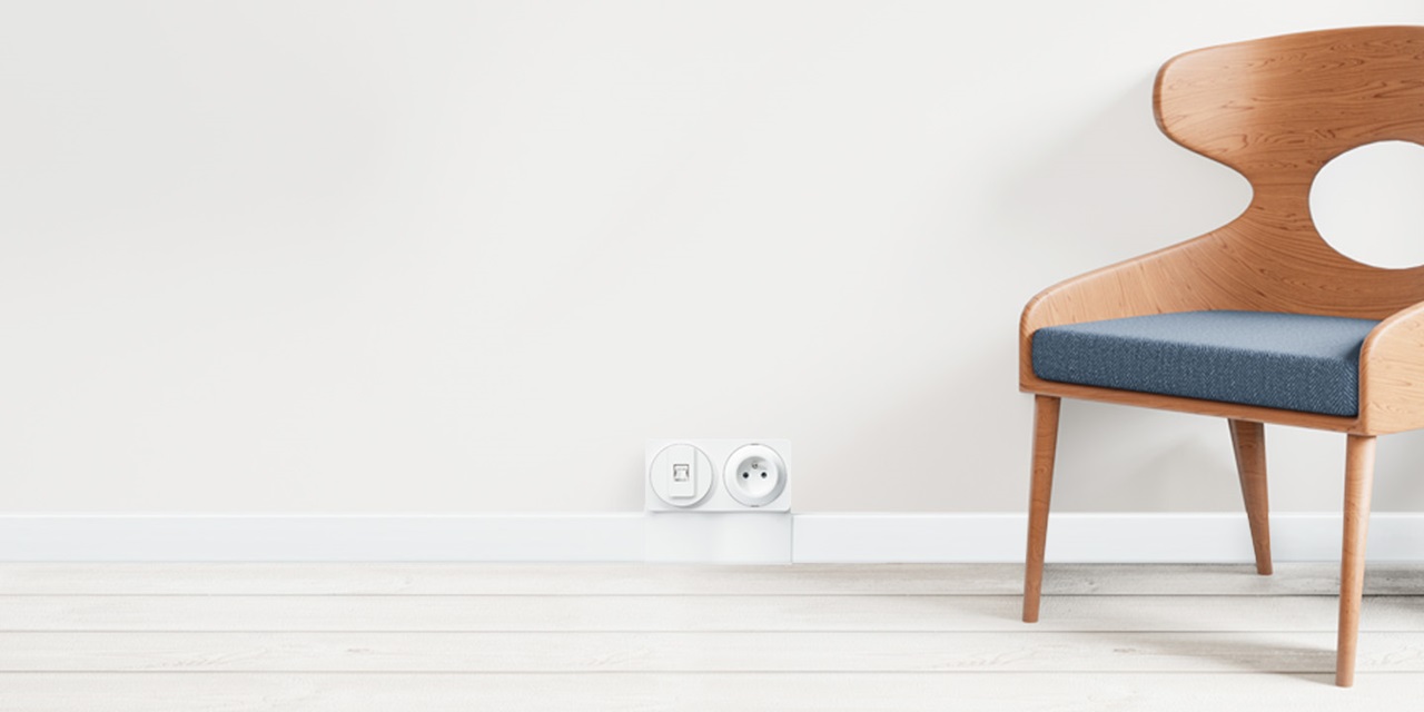 Minimalist interior with a modern wooden chair and a wall featuring an electrical socket and light switch